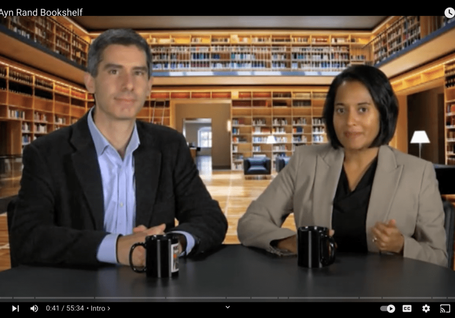 A man and woman sitting at a table in front of a library.